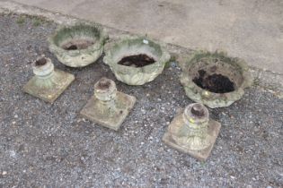 Three concrete planters raised on pedestal bases