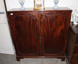 A Georgian mahogany side cabinet; the interior shelves enclosed by a pair of moulded panel doors