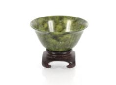 A small antique Chinese spinach green flared bowl, on hardwood base, 10cm dia.