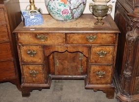 An 18th Century walnut kneehole desk, fitted two drawers above a blind frieze drawer and central