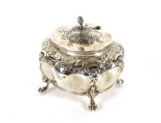 A late Victorian silver tea caddy, the hinged lid surmounted by a flambé finial, body embossed