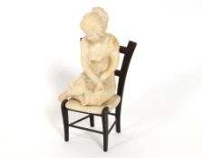 An alabaster figure of a seated child on a bronze