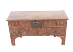 An 18th Century oak coffer, having square iron lock plate gouged and carved frieze raised on high