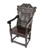 An 18th Century carved oak Wainscot chair having foliate decorated back panel above scroll arms