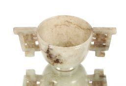 A small 19th Century Chinese jade cup, the twin handle carved with symbols, 9.5cm wide overall