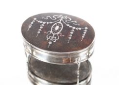 An oval silver and tortoiseshell trinket box, the lid decorated garlands and swags, raised on four