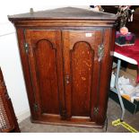 An 18th Century oak hanging corner cupboard, enclosed by a pair of moulded arched panel doors hung