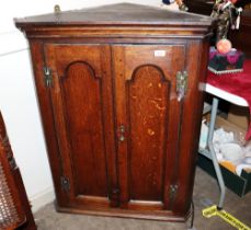 An 18th Century oak hanging corner cupboard, enclosed by a pair of moulded arched panel doors hung