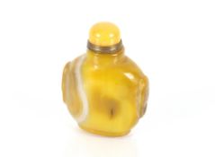 A yellow banded agate snuff bottle, with Peking glass stopper, Qing Dynasty, carved mask to the