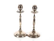 A pair of George V silver candlesticks, the nozzle shaped sconces above wide drip pans on baluster