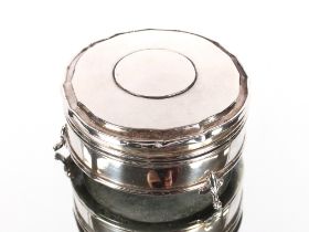 A circular silver trinket box, the shaped hinged lid revealing a silk lined interior raised on three