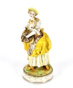 A 19th Century German porcelain figure of a lady in yellow dress with basket of flowers, raised on a