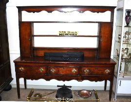 A 18th Century oak dresser, the plate rack flanked by cupboards, three drawers below on a shaped