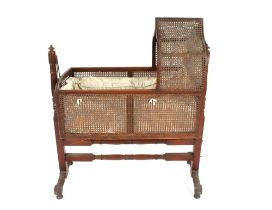 A Victorian mahogany crib, having wicker sides and top suspended from two turned columns united by