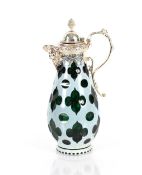 A green and white overlaid glass claret jug of baluster form, having foliate engraved white metal