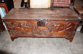 An antique carved oak continental coffer, having square iron lock plate, the frieze with vine and