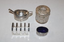 A silver toast rack; a silver salt with blue glass liner; a silver mustard lacking liner with spoon;