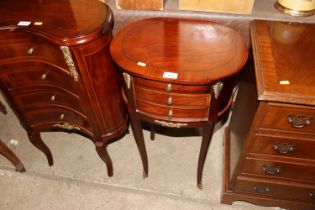 An oval topped bedside table fitted three drawers