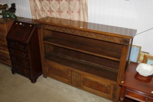 A carved oak bookcase with fitted cupboard below