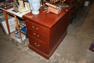 A dark wood three drawer deskside filing cabinet