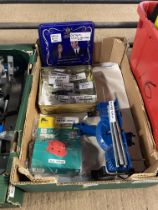 A box containing a small mitre saw, a tin containing drill measure stoppers, drill depth controller,