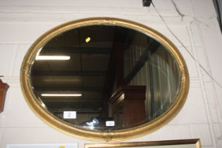 A decorative oval gilt framed wall mirror
