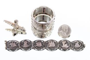 A white metal napkin ring with foliate and stylise