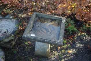 A square concrete bird bath on concrete plinth