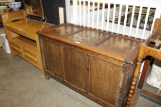 An oak coffer with triple panel front and lid