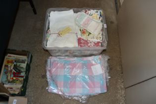 A box containing various bed covers and table nape