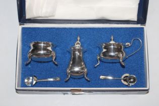 A silver plated three piece cruet set with spoons