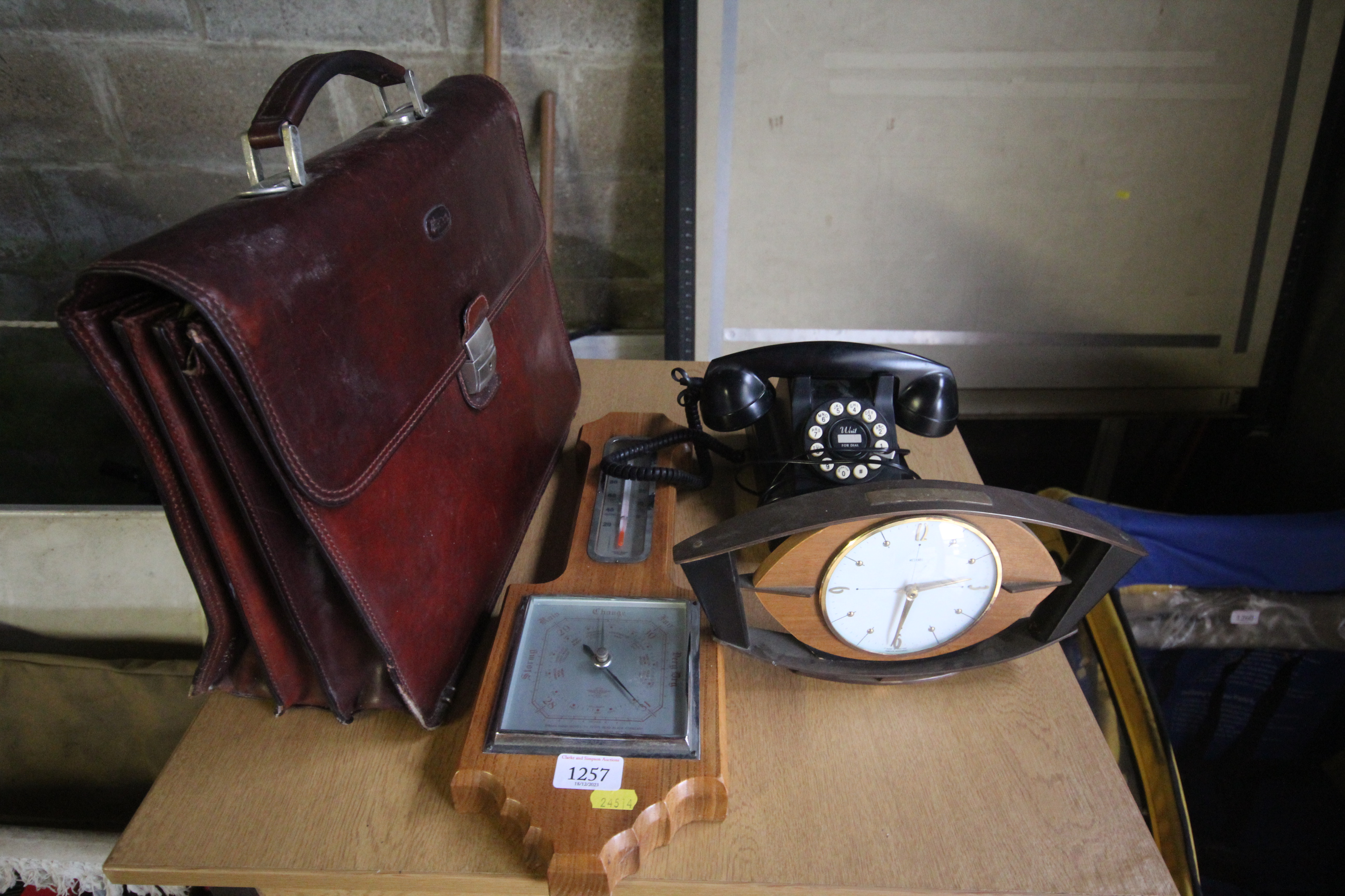 A leather briefcase, a wall hanging barometer, an