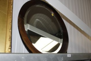 A circular wooden framed and bevel edged wall mirr