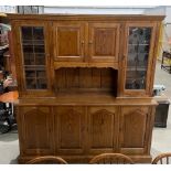 A large oak dresser/wall unit with upper leaded glazed doors flanking a two door cupboard over