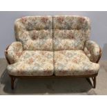 An Ercol medium elm two seater settee with light brown floral patterned cushions (saleroom