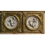 Two reproduction wall plaques in relief (Puttii) in ornamental gilt frames each 32cm x 32cm
