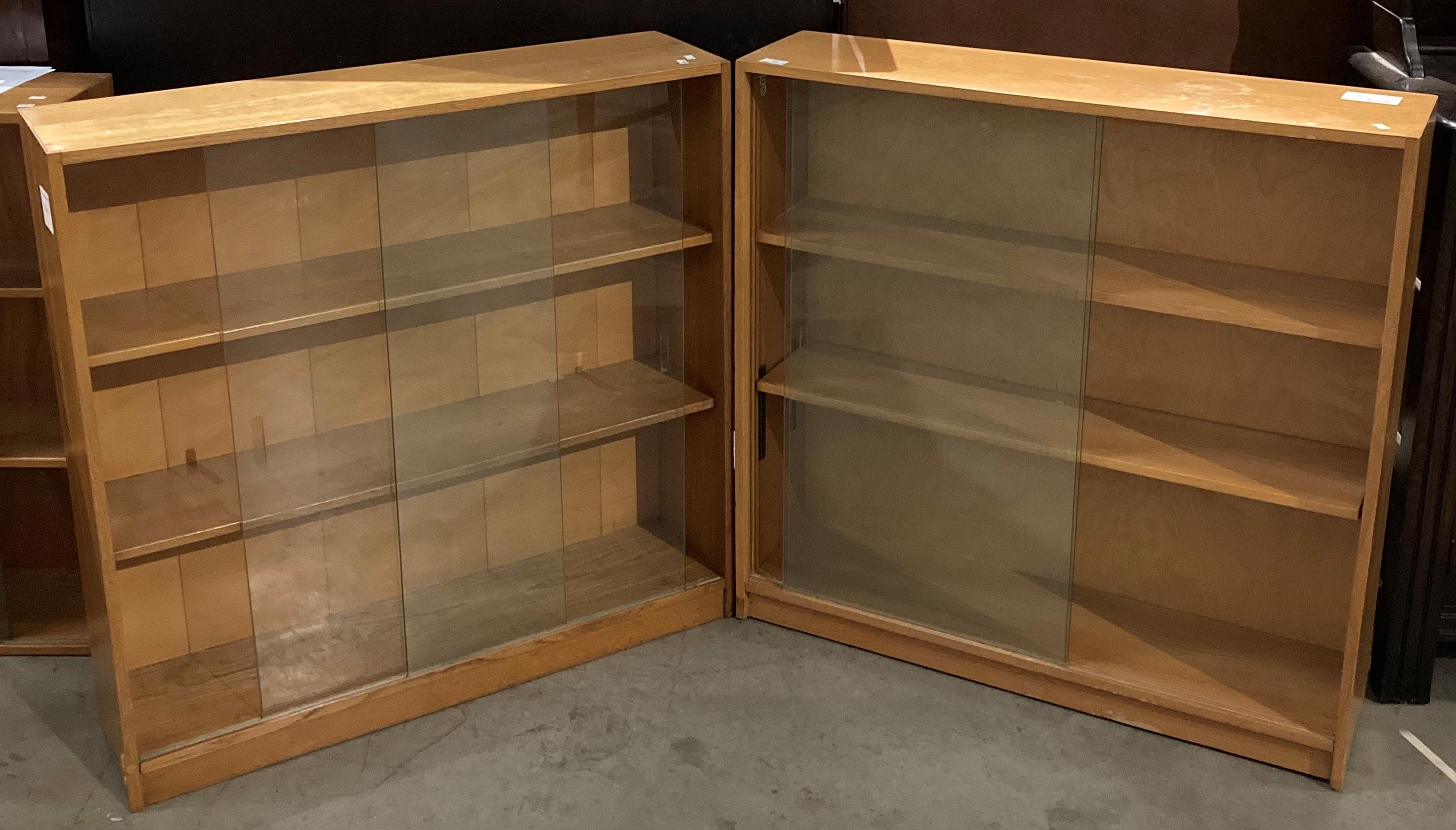 Two light oak three shelf bookcases, each with two glass sliding doors - each 89cm x 89cm x 22.