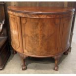 A 1930s walnut half moon cabinet with centre door on short cabriole legs and claw and ball feet