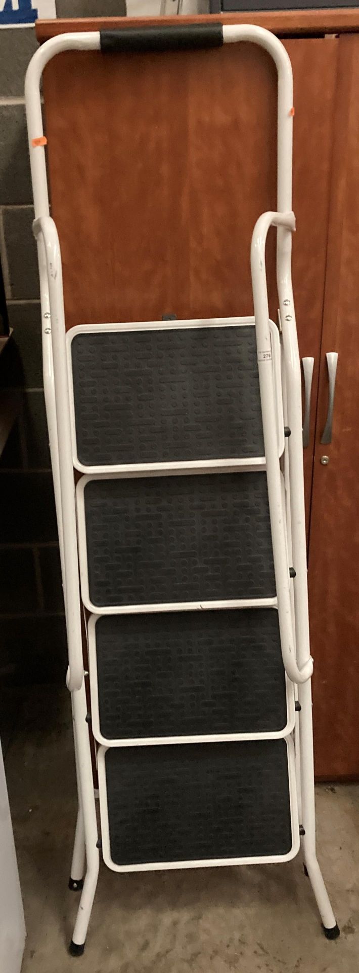 A white metal four step folding stepladder