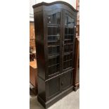 A tall oak arched top bookcase with twin leaded glazed doors over two door cupboard,