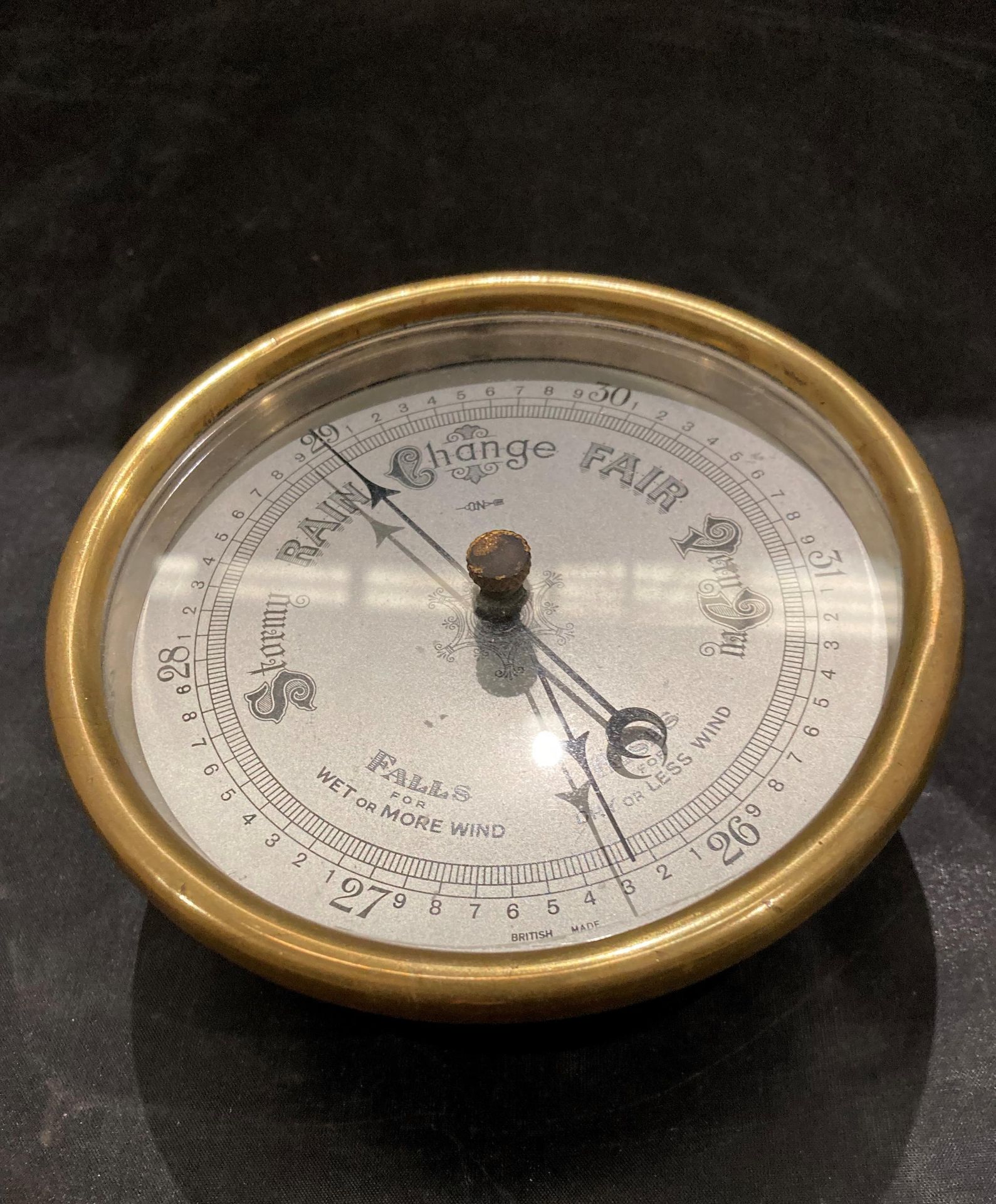 A small circular barometer in metal case with brass rim,