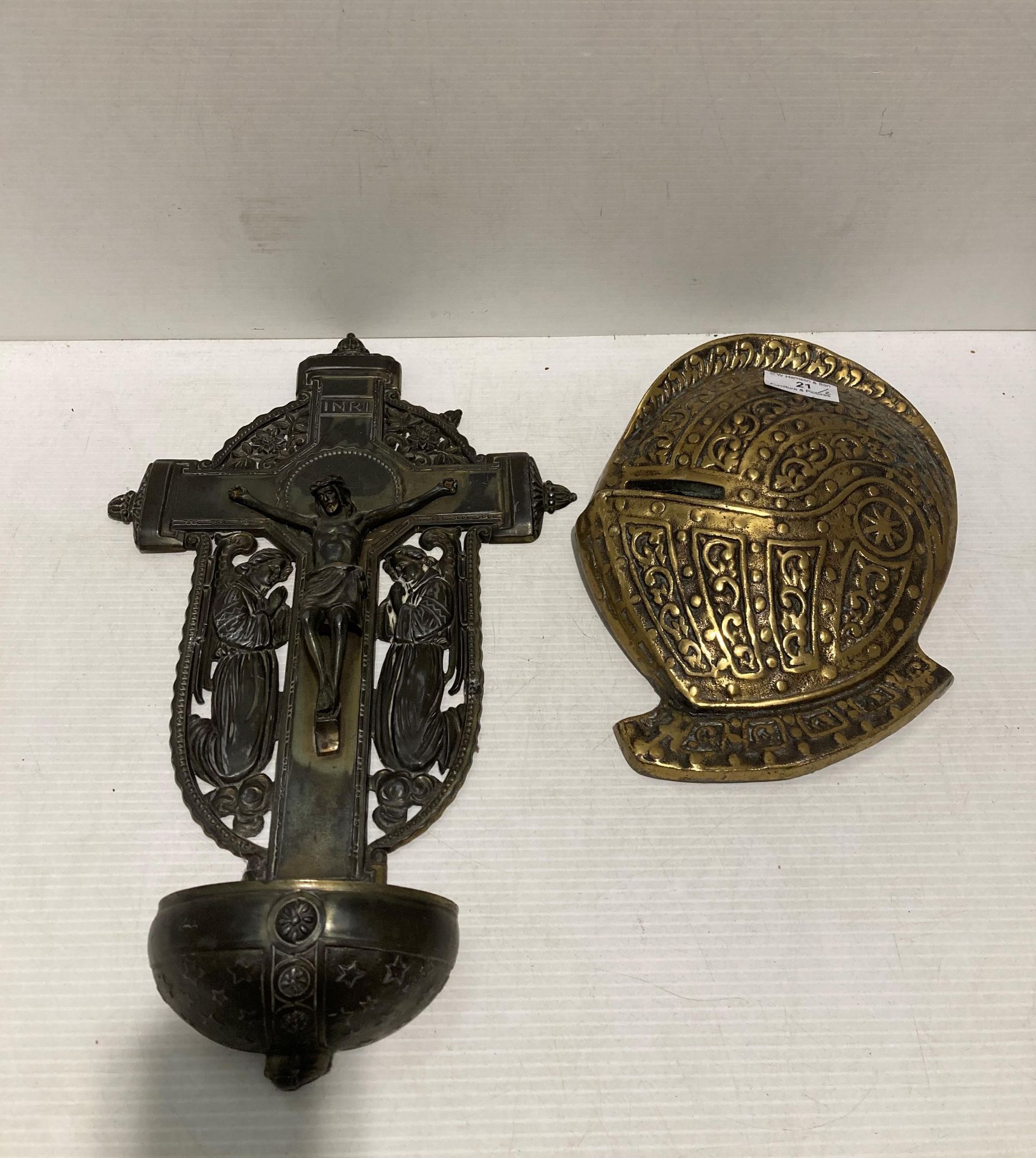 Brass plaque of a medieval knights helmet and a metal wall plaque of Jesus on a cross (saleroom