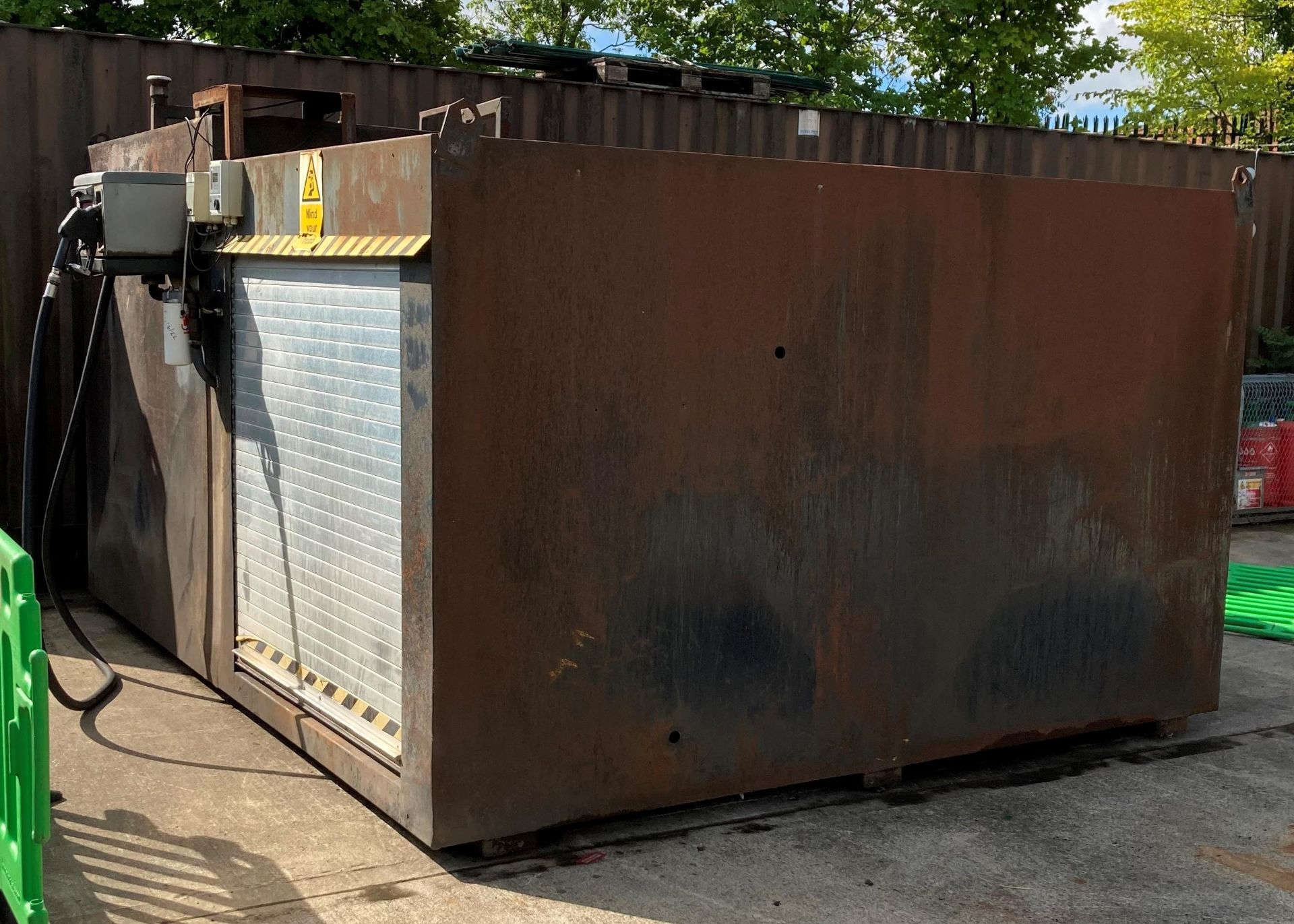 A metal framed 10000 litre bunded fuel tank with side storage compartment with aluminium roller