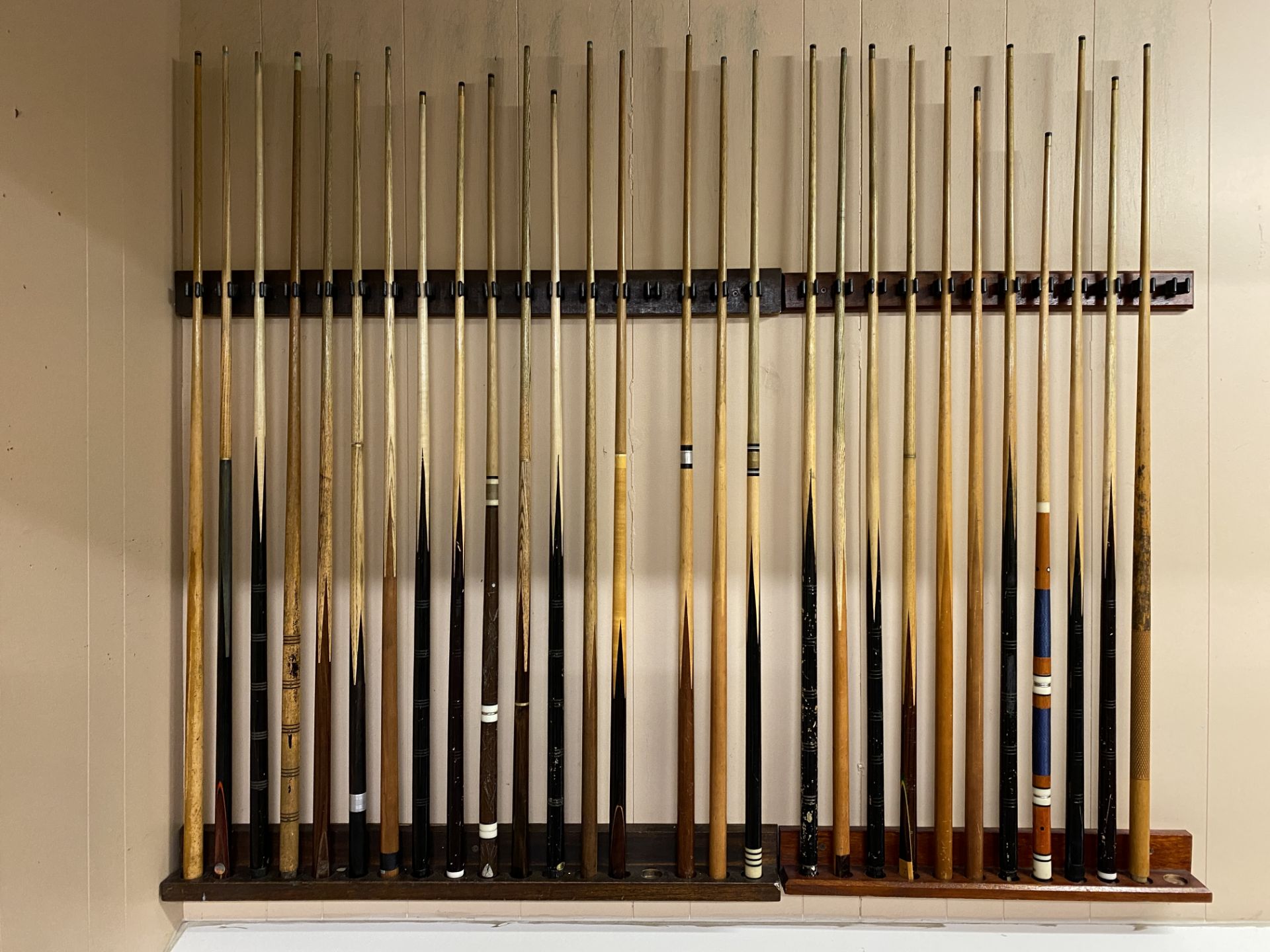 Wall rack and contents - 28 assorted snooker and pool cues.