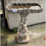A concrete bird bath on squirrel pedestal,
