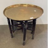 An Indian Benares brass topped circular table with folding wooden base,