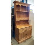Pine kitchen dresser with two shelf plate rack over five small drawers and two door cupboard below,