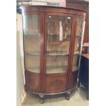 A mahogany bow fronted glass china cabinet with inlay, on claw and ball feet, complete with key,