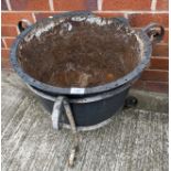 A cast metal cauldron planter (damage to rim) in a metal basket,