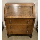 An oak bureau with fall front, internally fitted with four sections and three drawers below,